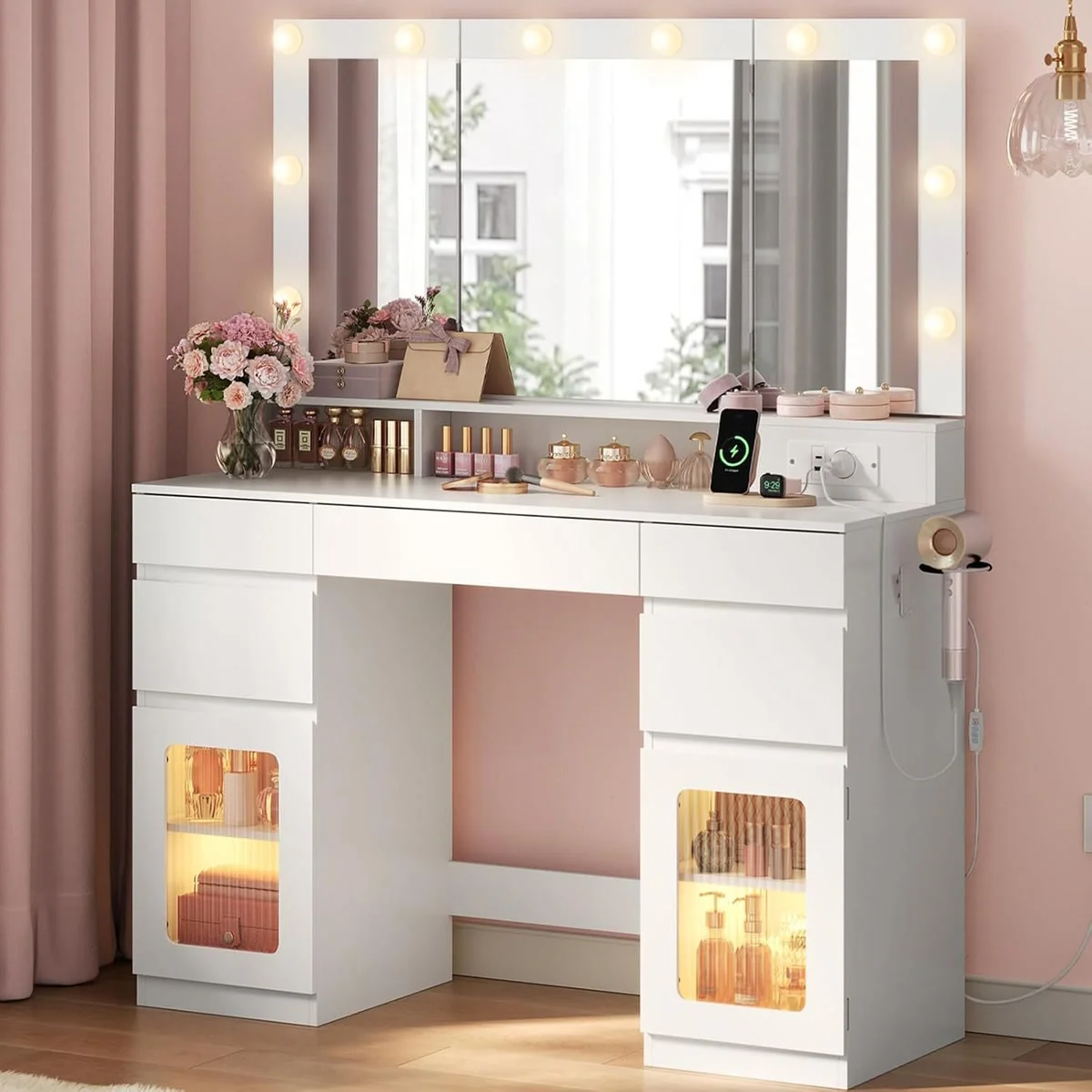 Tocador de maquillaje blanco de 104 cm en un dormitorio, con las 10 bombillas LED encendidas alrededor del espejo triple