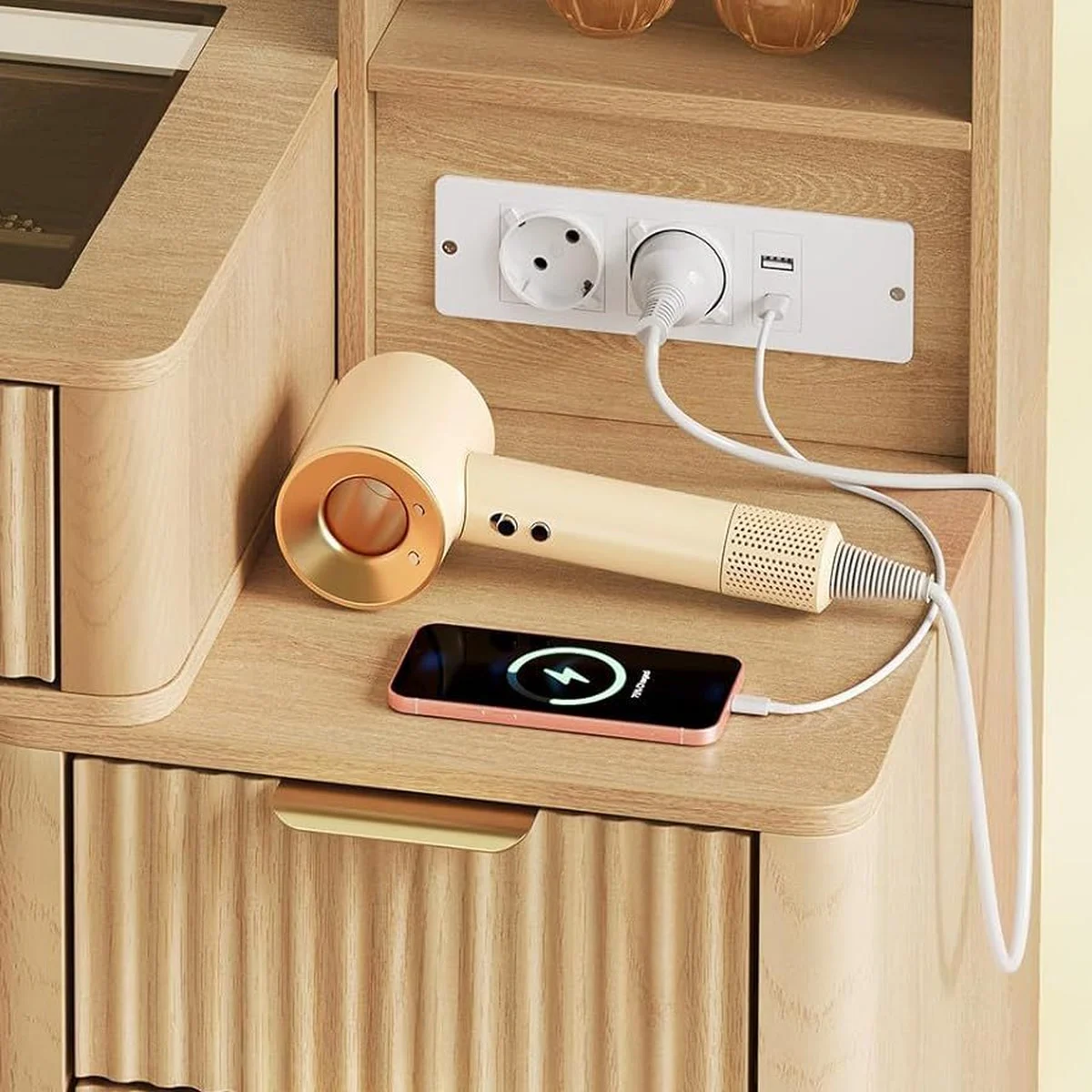 Los 2 enchufes y los puertos USB y USB-C del tocador, con un secador y un móvil enchufados
